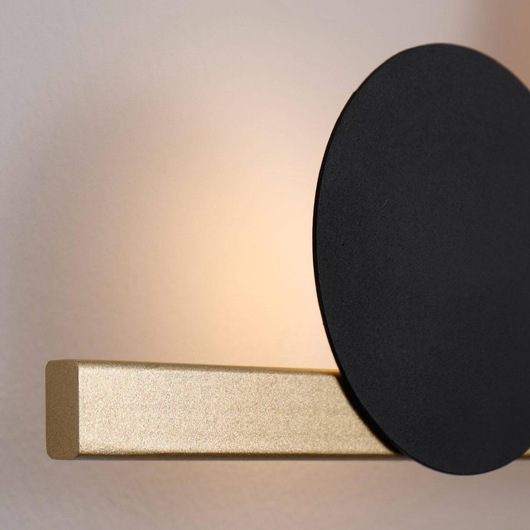 Modern LED wall sconce featuring a black circle and gold base, perfect for bedroom accent wall lighting.