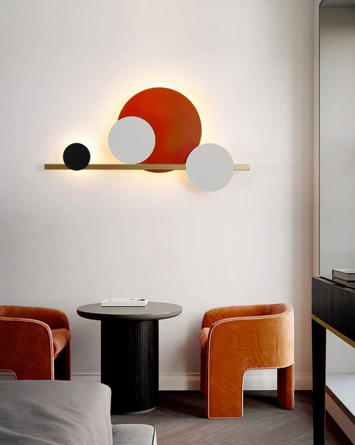 Modern circle LED wall light above a stylish table and chairs, perfect for accent wall lighting in a bedroom.