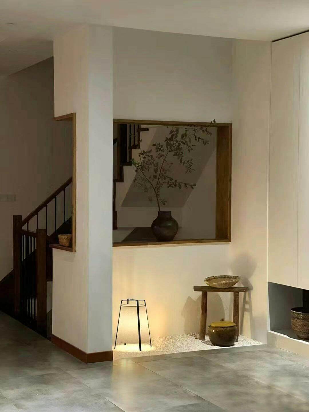 Cozy living room corner featuring a stylish lamp, wooden stool, and decorative vases, perfect for a vintage-inspired decor.