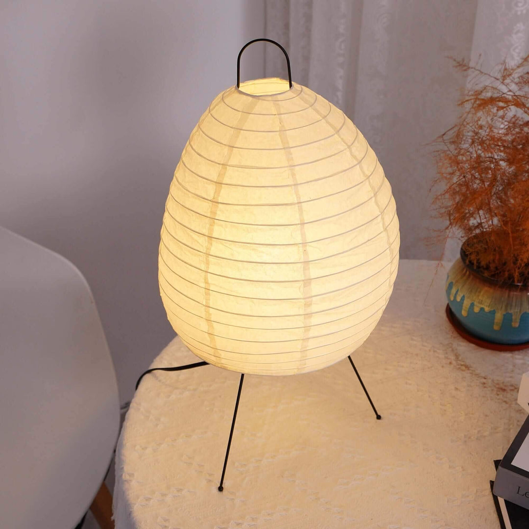 Akari 1N minimal Japandi table lamp, white, round shape, illuminating soft light on a side table, modern decor.