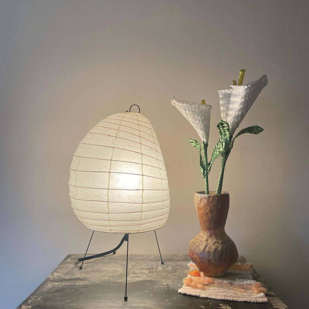 Akari 1N Japandi table lamp with minimalist design, white shade, beside a unique flower vase.