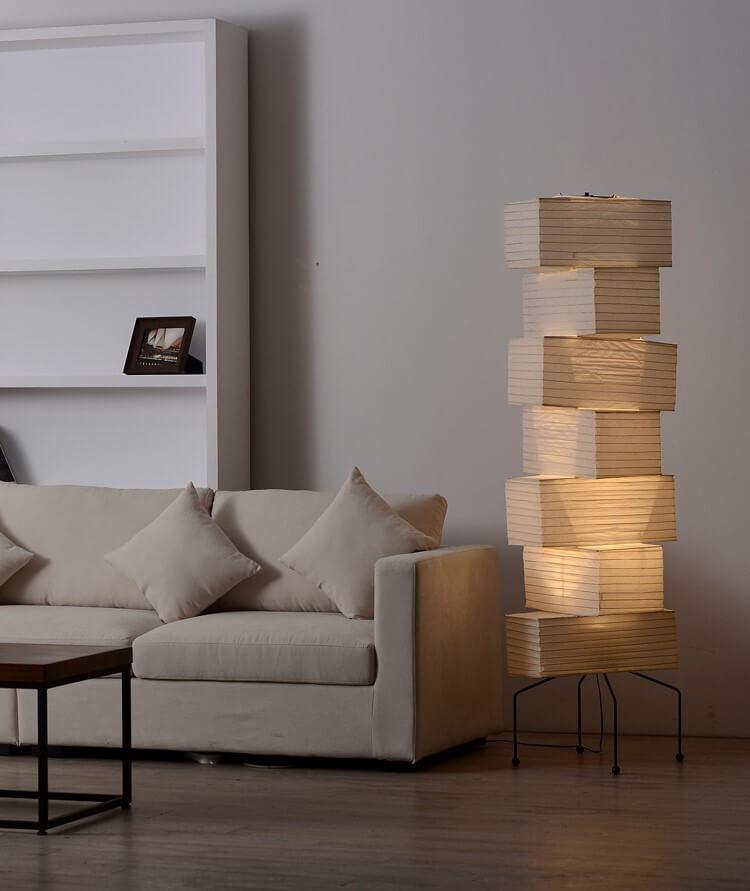 Minimalist Akari UF4-L10 white rice paper floor lamp beside a cozy sofa in a contemporary living room setting.