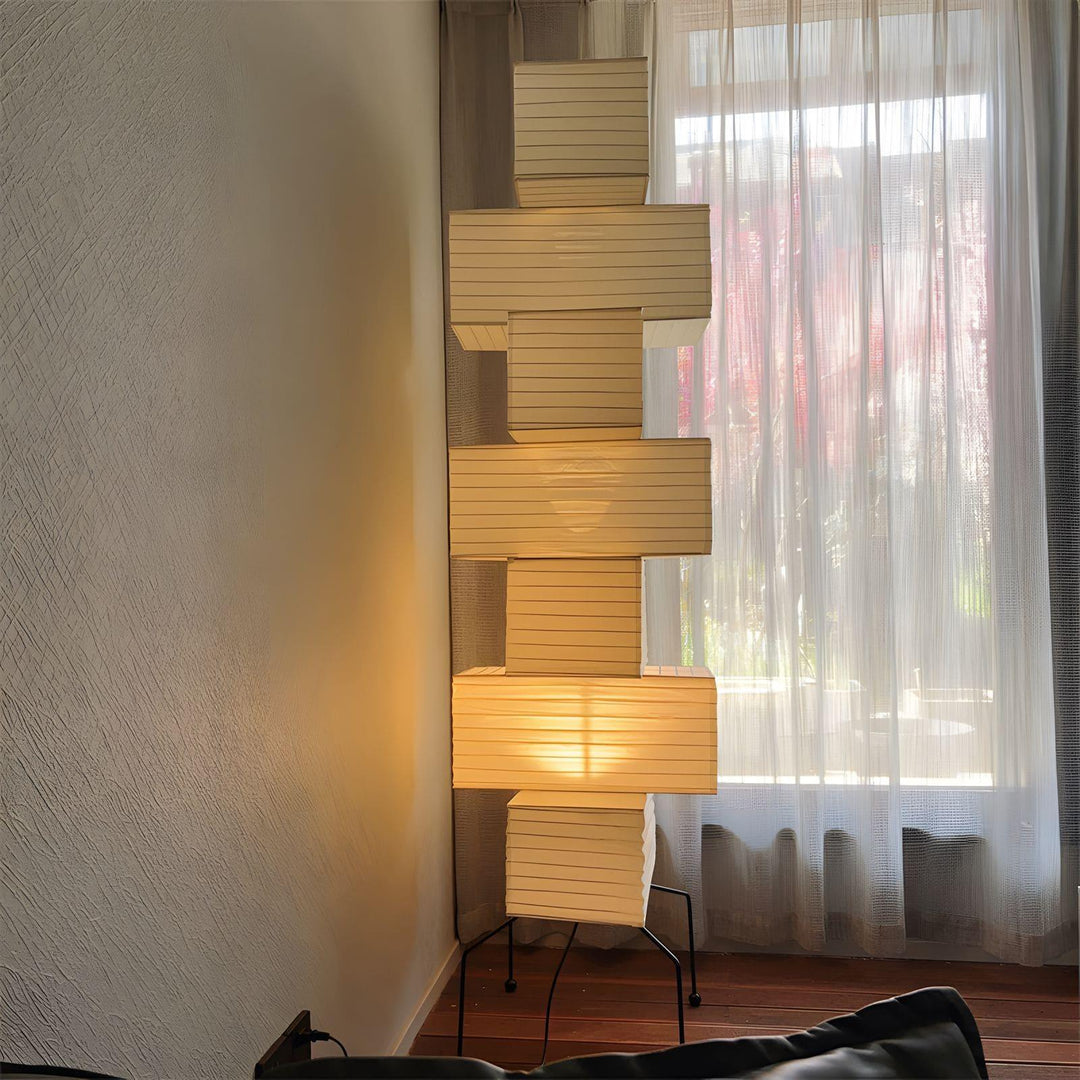 Minimalist Akari UF4-L10 white rice paper floor lamp casting warm light beside a curtain, perfect for modern decor.