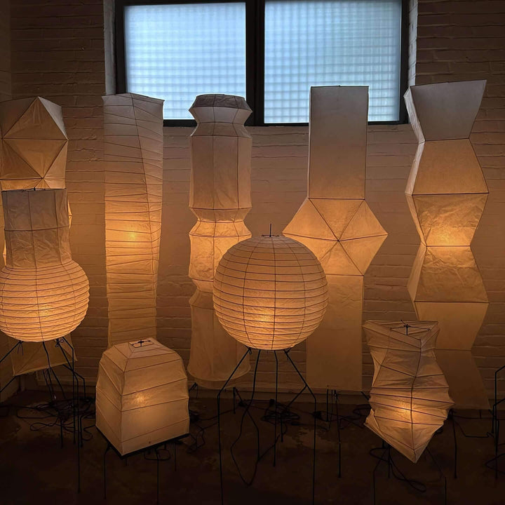 A collection of elegant white rice paper floor lamps with warm lighting, showcasing minimalist Japanese design aesthetics.