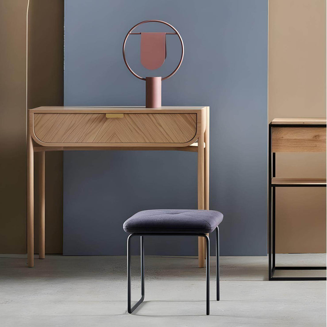 Modern furniture setup featuring a stylish console table, decorative lamp, and upholstered stool in a contemporary interior.