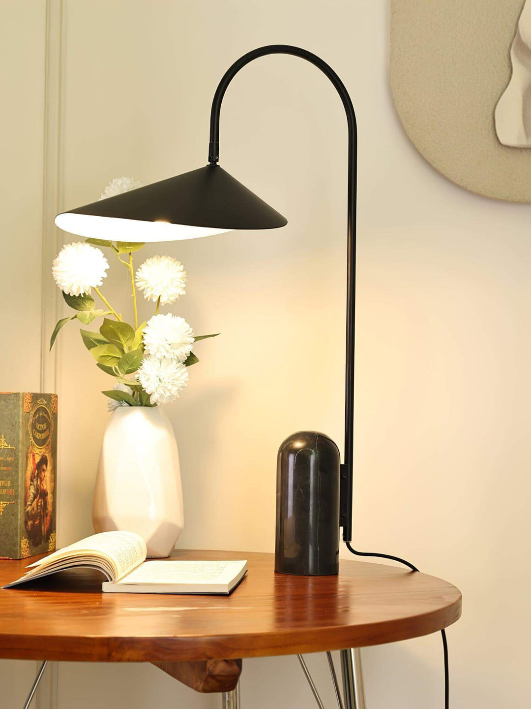 Arum Table Lamp on a wooden table, featuring a modern black design, perfect for office or living room decor.
