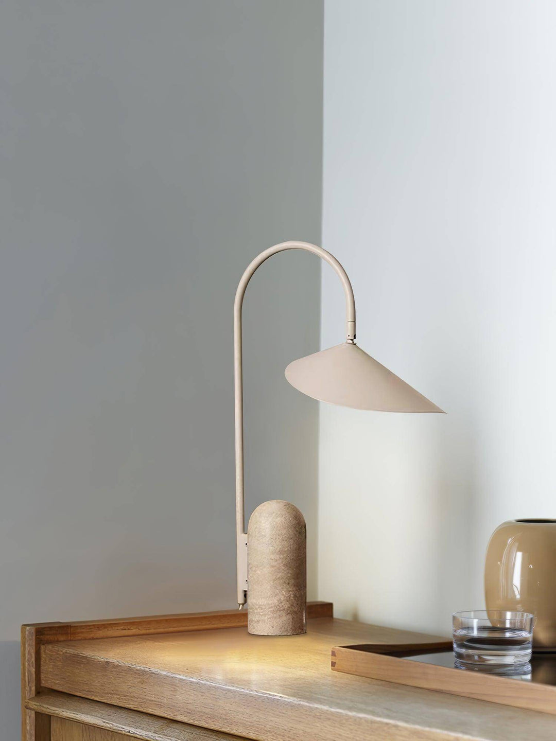 Modern office table lamp with beige shade and curved neck, illuminating a stylish wooden surface.