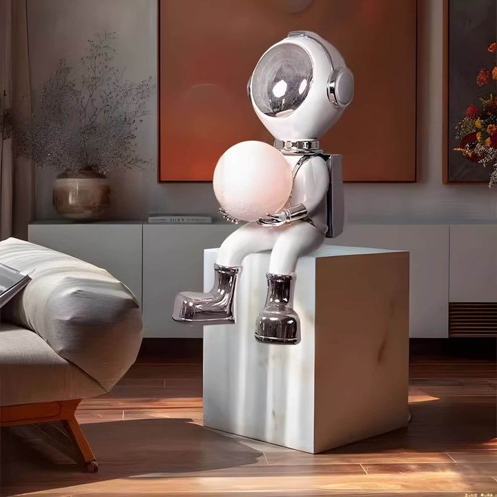 Sculptural astronaut lamp sitting on a modern marble pedestal, adding a whimsical touch to contemporary decor.