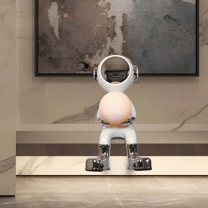 Sculptural astronaut figure holding a glowing orb, modern decor for a stylish interior.