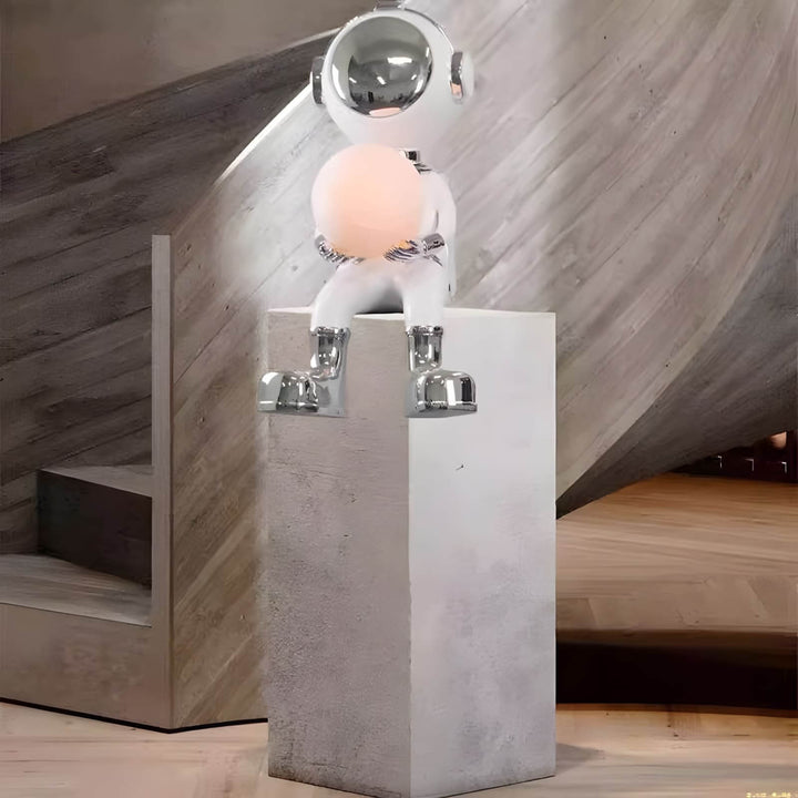Sculptural astronaut lamp design featuring a chrome finish and round light, perfect for modern decor.