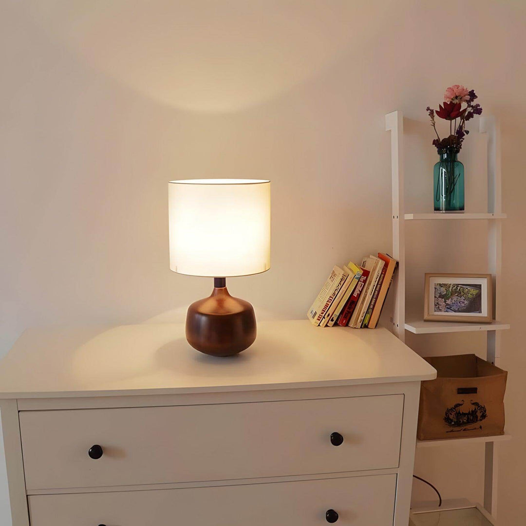 Stylish Bethel wood table lamp glowing on a dresser, showcasing mid-century modern and japandi design elements.
