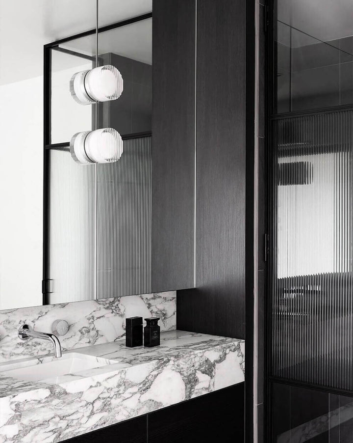 Modern bathroom design featuring marble countertop and stylish pendant lights for a sleek ambiance.