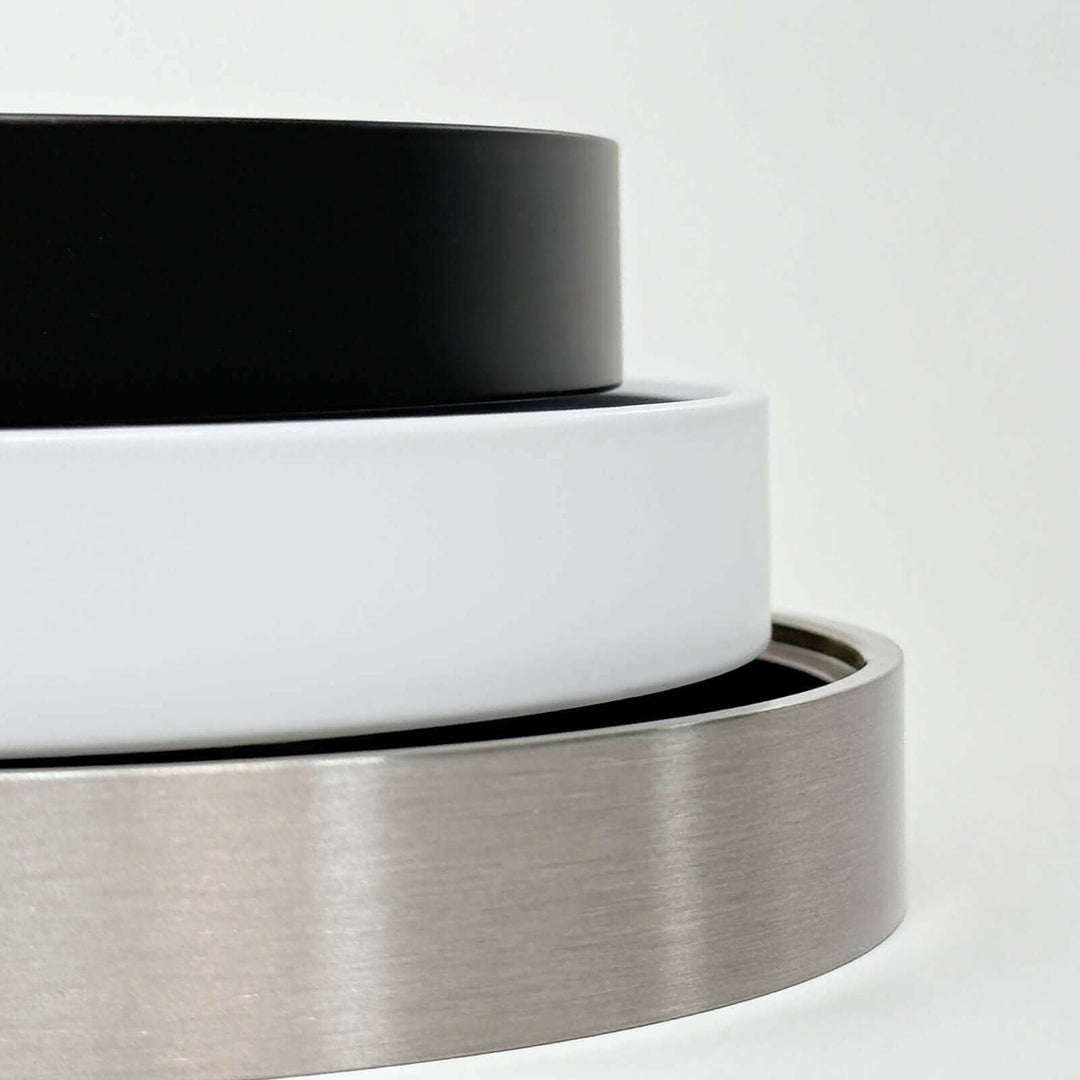 Close-up of matte black, white, and nickel backplates for Dimple Wall Sconce, showcasing sleek, modern design options.