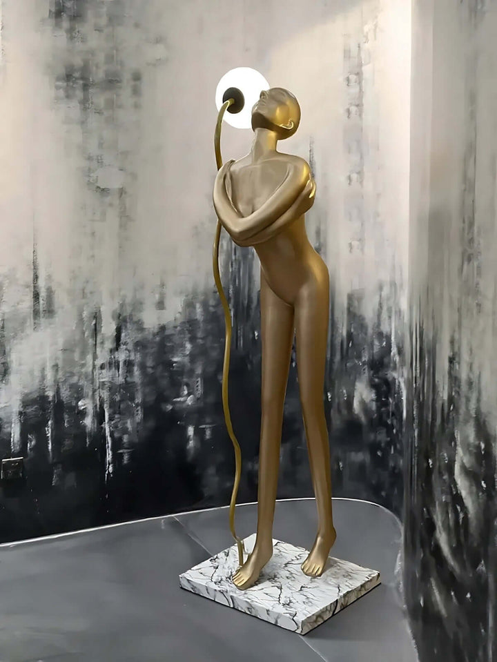 Sculptural art deco floor lamp in a stylish living room, featuring a golden figure and a marble base.