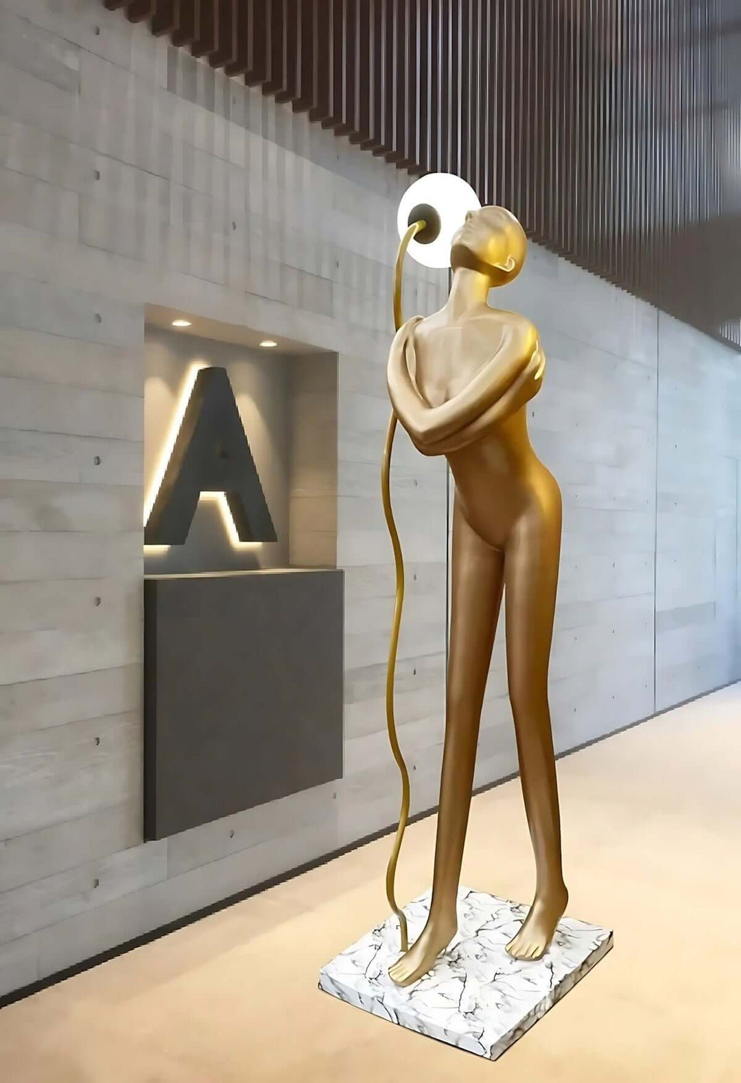 Sculptural floor lamp in the form of a golden figure against modern wall design, perfect for art deco interiors.