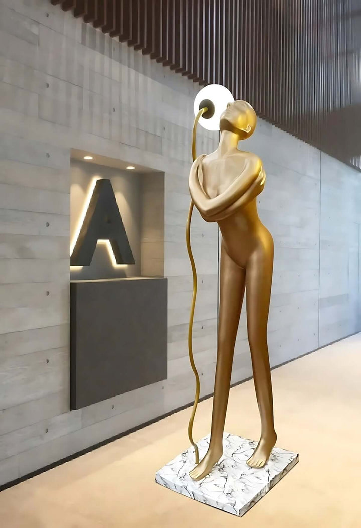 Sculptural floor lamp in the form of a golden figure against modern wall design, perfect for art deco interiors.
