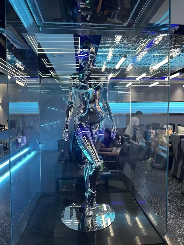 Sleek chrome robotic sculpture displayed in a modern glass case with blue LED lighting.