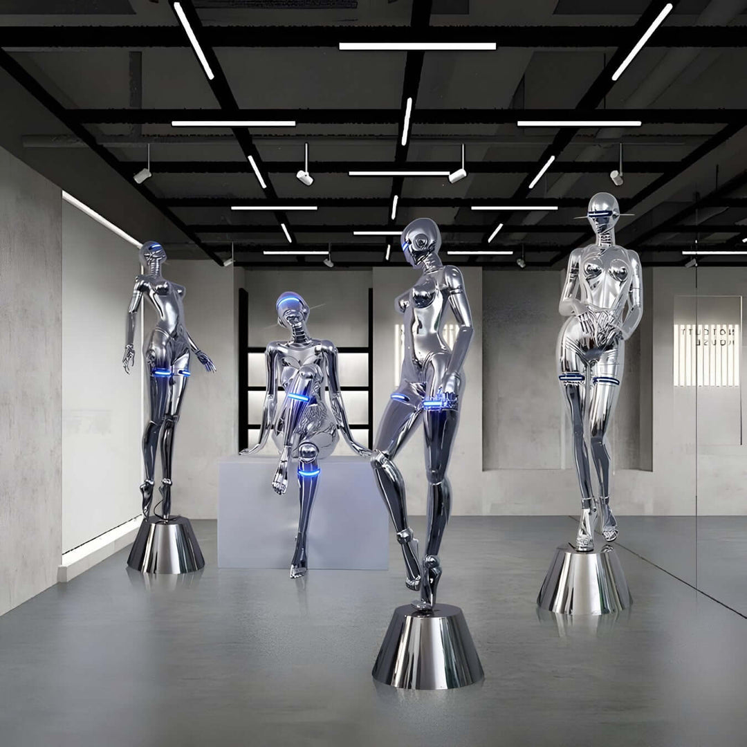 Sculptural display of four modern silver mannequins illuminated in a sleek art gallery setting.