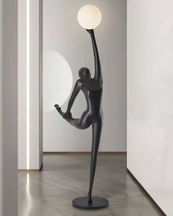 Sculptural floor lamp in a modern hallway, featuring a dancer silhouette holding a round light for stylish illumination.