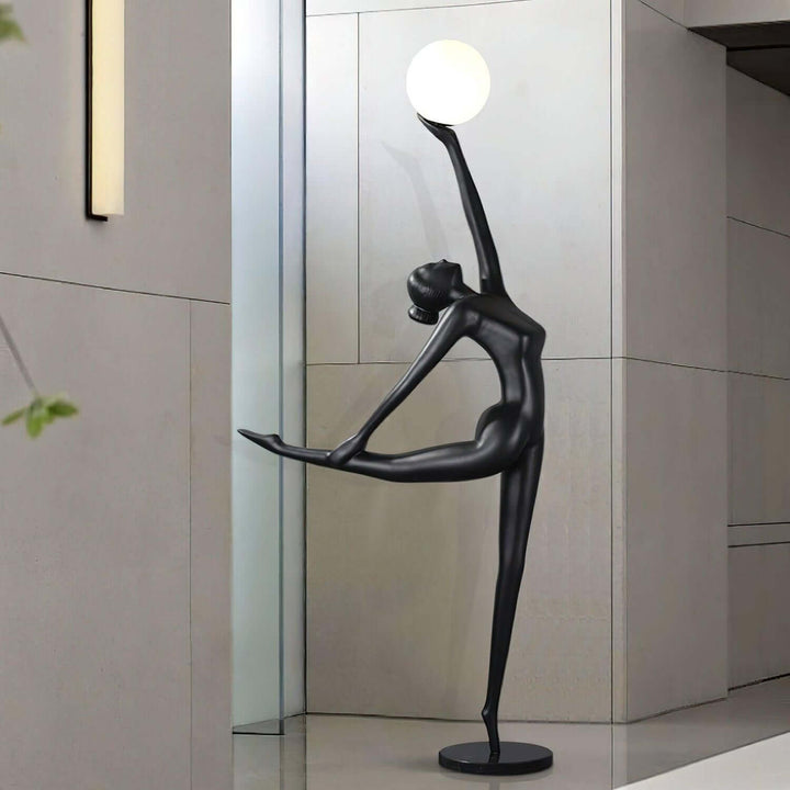 Sculptural black floor lamp featuring a dancer silhouette holding a globe, perfect for living room decor.