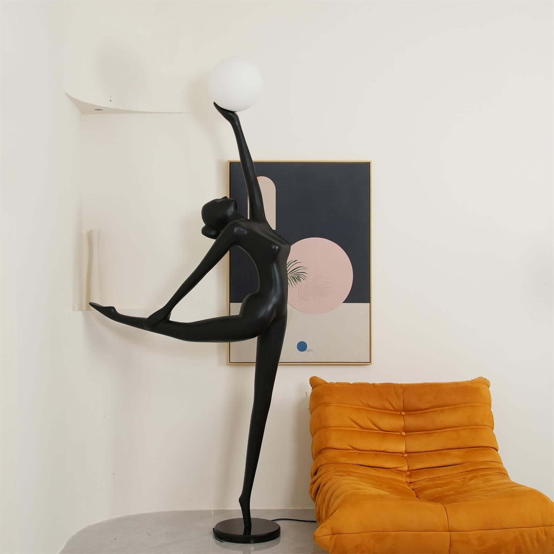Sculptural black art deco floor lamp in a stylish living room setting with orange chair and modern artwork.