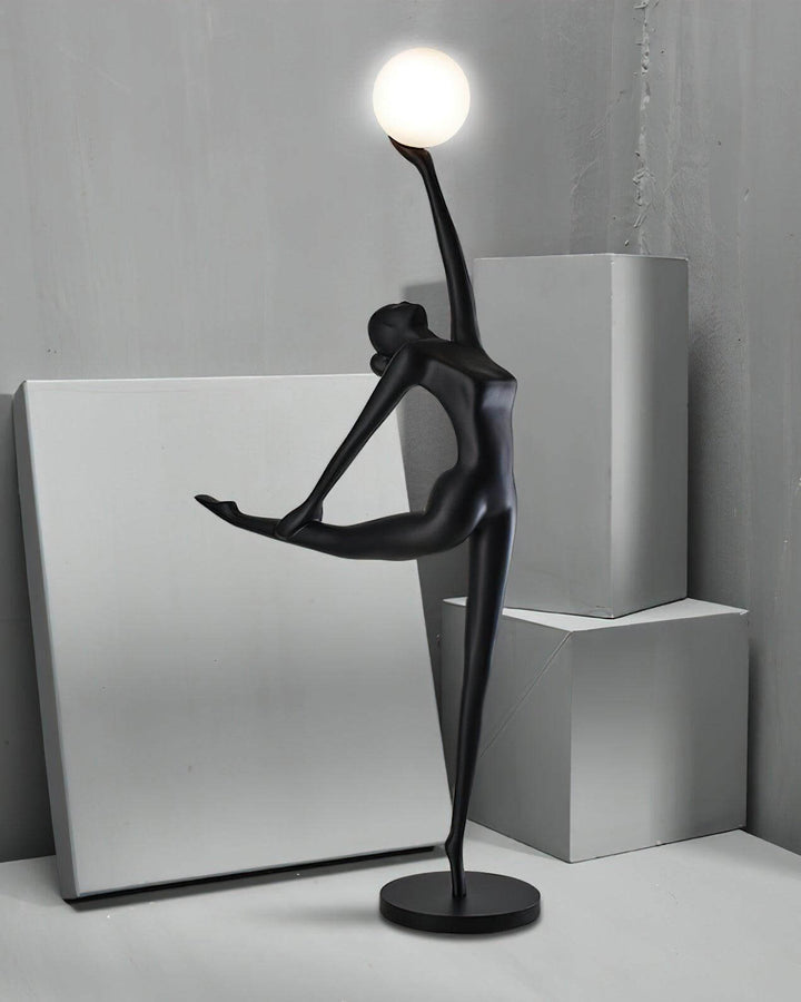Sculptural Elvani resin floor lamp with a graceful figure holding a glowing orb, perfect for modern living room decor.