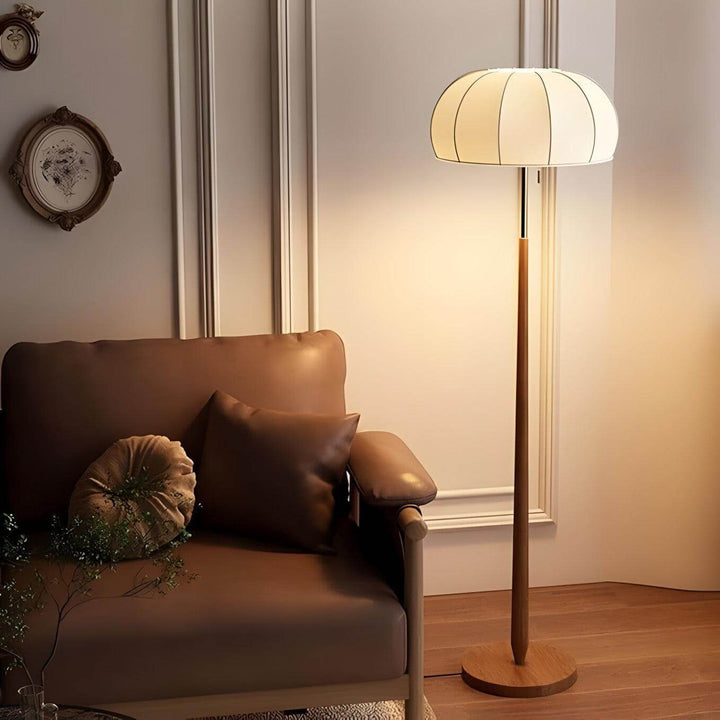 Gorra floor lamp in mid-century style with wood base, illuminating a cozy living area, perfect for farmhouse decor.