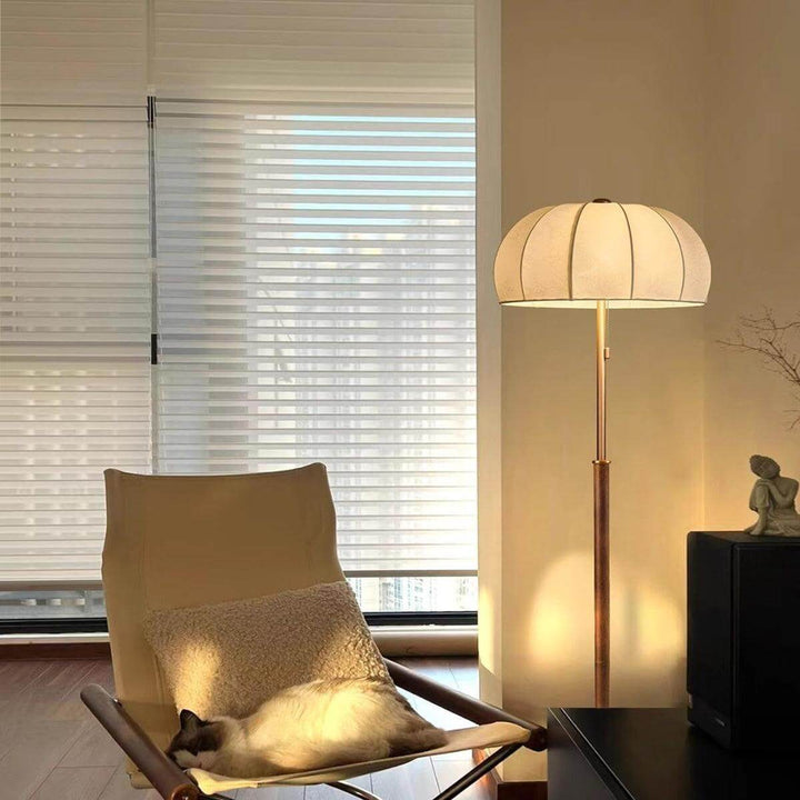 Gorra Floor Lamp in mid-century style, illuminating a cozy room with a modern farmhouse vibe, paired with a relaxing chair.