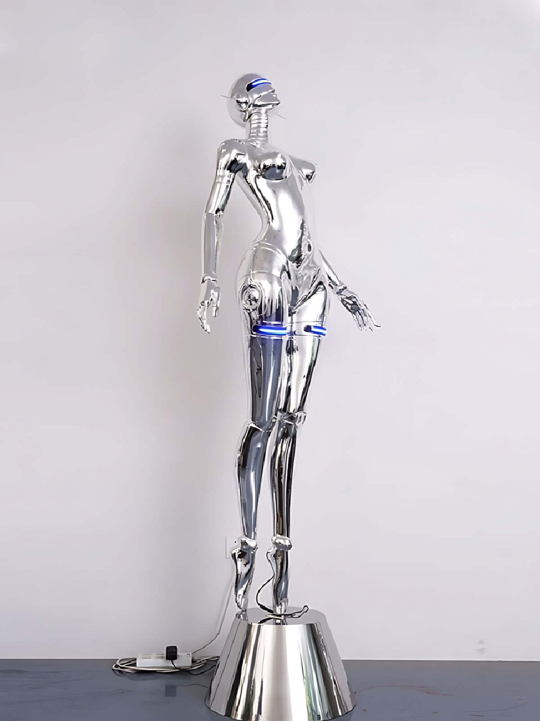 Sculptural floor lamp in the shape of a human figure, featuring a silver finish and blue accents, ideal for modern living rooms.
