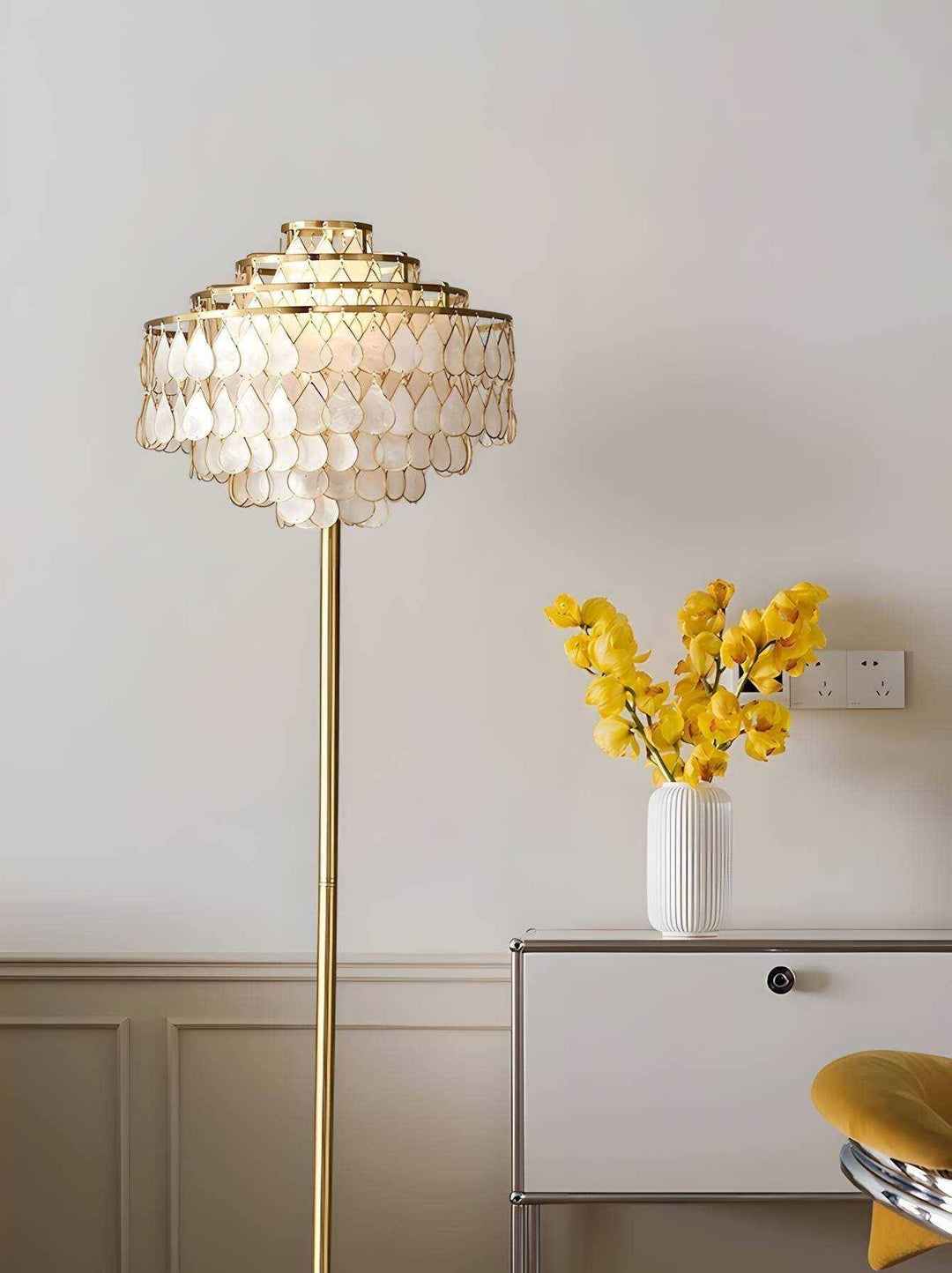 Teardrops shell floor lamp in gold beside a vase of yellow flowers, ideal coastal floor lamp for bedroom decor.