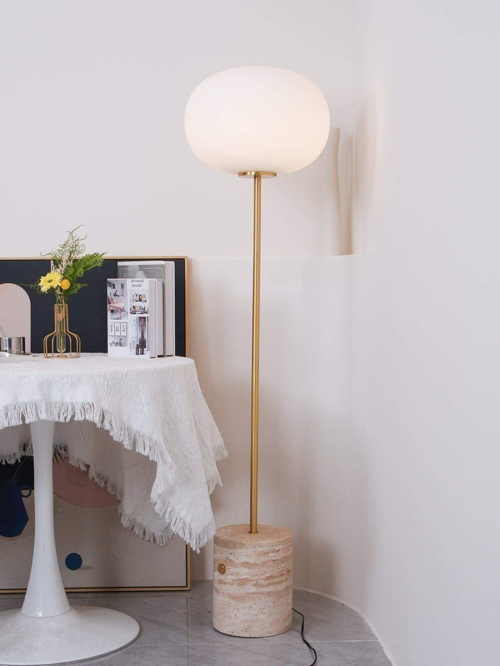 Modern floor lamp in living room, featuring a round glass shade and a stylish base for a cozy reading nook.