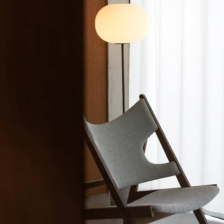 Modern floor lamp illuminating a stylish chair in a cozy living room setting, ideal for reading.