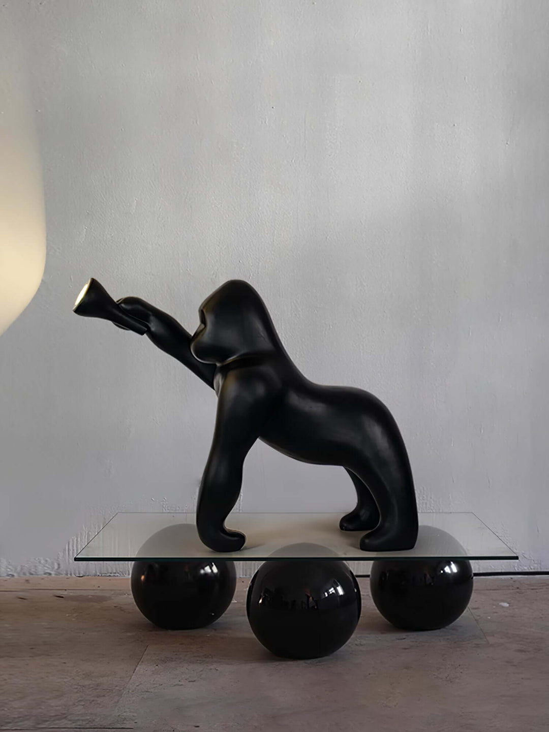 Kong sculpture floor lamp featuring a black gorilla design on a glass table, ideal for modern decor.