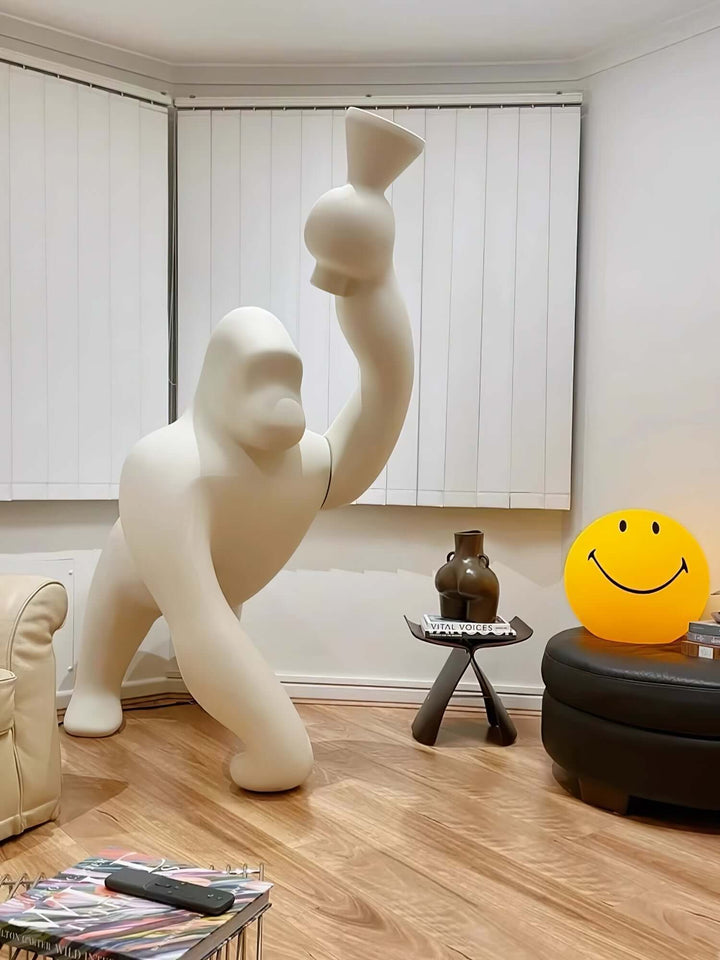 Sculptural floor lamp in a living room setting, featuring a playful gorilla design holding a vase.