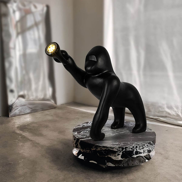 Sculptural floor lamp resembling a black gorilla holding a light, featuring a stylish marble base in a modern living room.