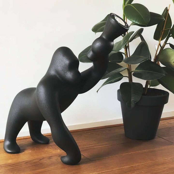 Kong sculpture floor lamp in black design, styled beside a potted plant, adding a unique touch to modern living spaces.