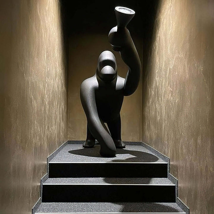 Sculptural floor lamp in the shape of a monkey, elegantly displayed on steps with a modern backdrop.