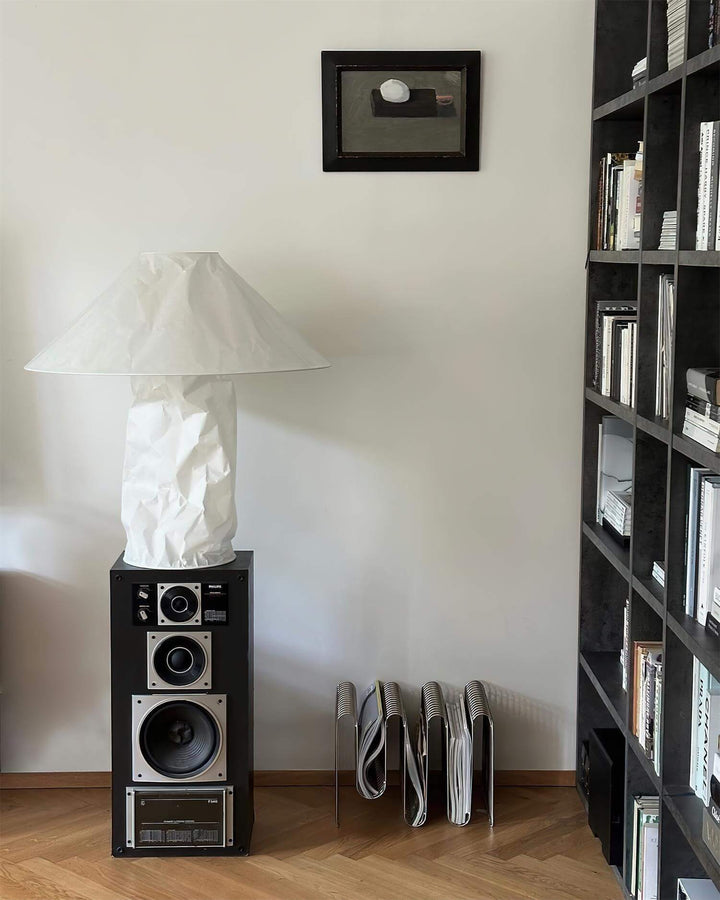 Minimal table lamp in a stylish living room setting beside a speaker, featuring a white finish, ideal for bedroom bedside lighting.