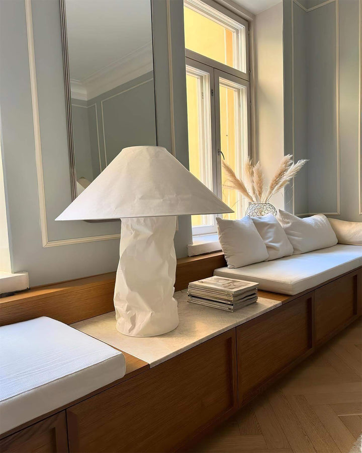 Minimal table lamp in white, enhancing a stylish interior on a wooden bench with natural decor.
