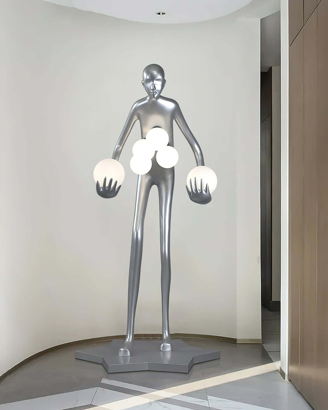 Sculptural floor lamp in a modern hallway, featuring a tall metallic figure holding globes of light, showcasing art deco style.