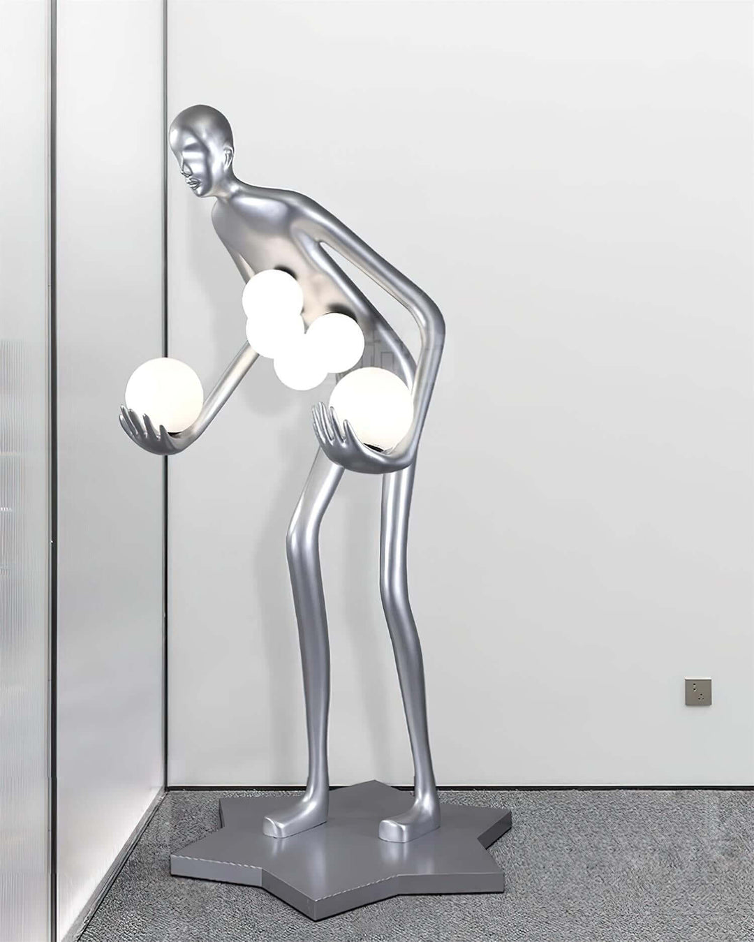 Sculptural floor lamp in silver with a unique human-like shape, holds glowing orbs, perfect for contemporary art deco decor.