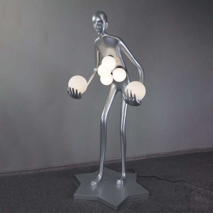 Sculptural floor lamp resembling a human figure, holding glowing orbs, perfect for modern art deco living room lighting.