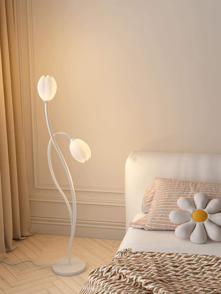 Modern Manta Flower Floor Lamp in white, features minimalist design, illuminating a cozy bedroom with floral accents.