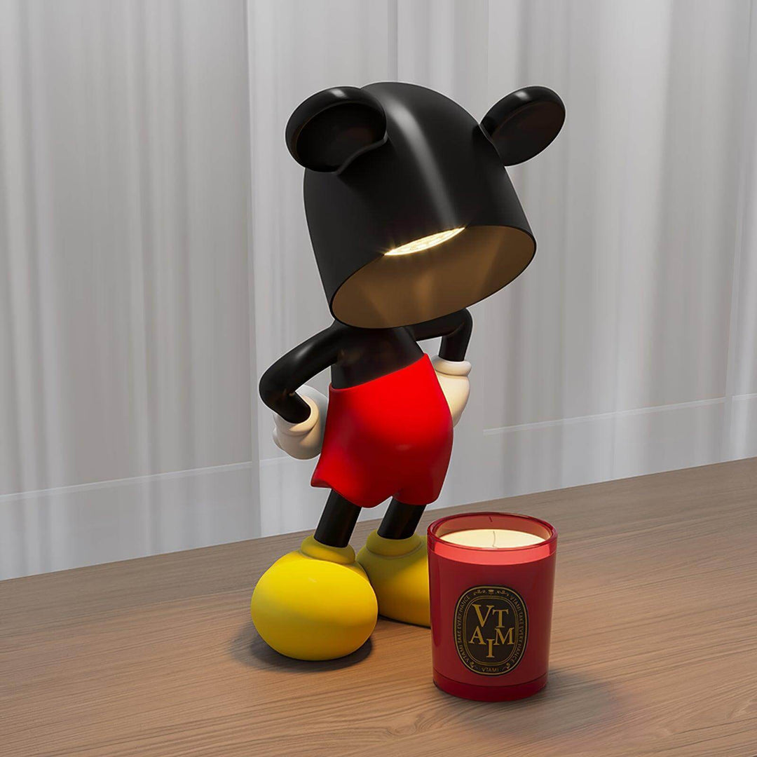Mickey Table Lamp with sculptural design, modern black art deco style, beside a scented candle on a wooden table.