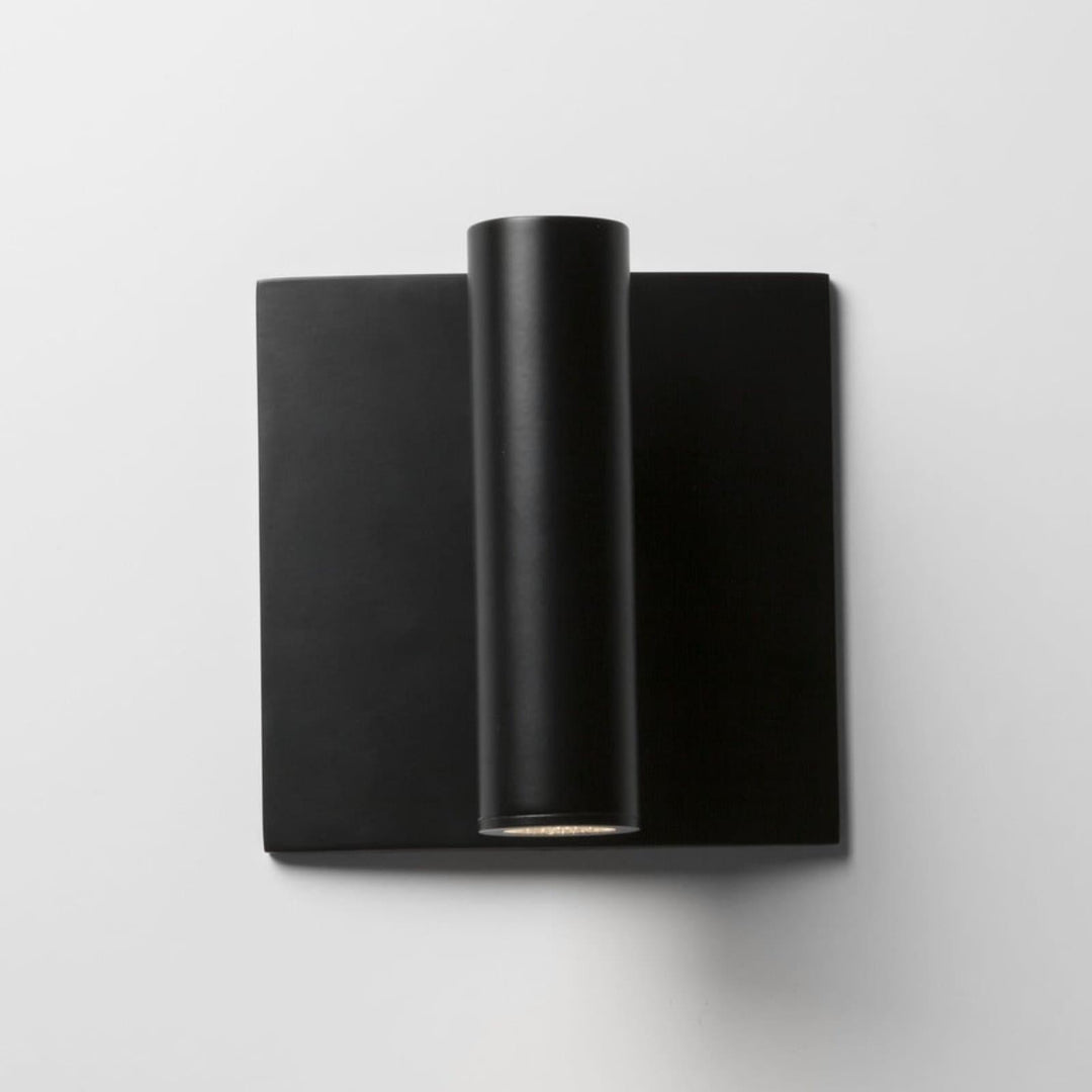 Modern black flush mount wall sconce with cylindrical lamp, perfect for minimalist decor and bedside reading.