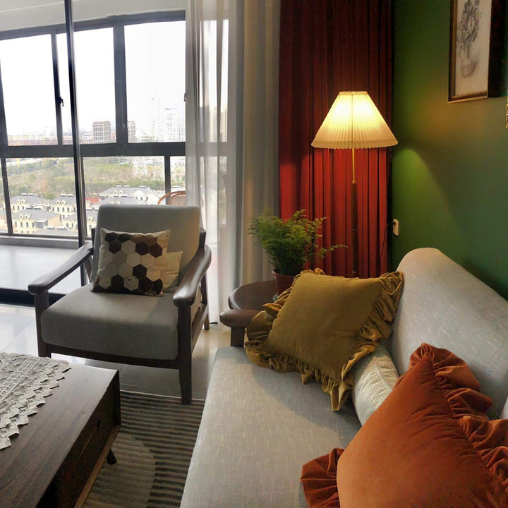 Mid century pleated floor lamp illuminating a cozy living room with wooden accents and stylish pillows.
