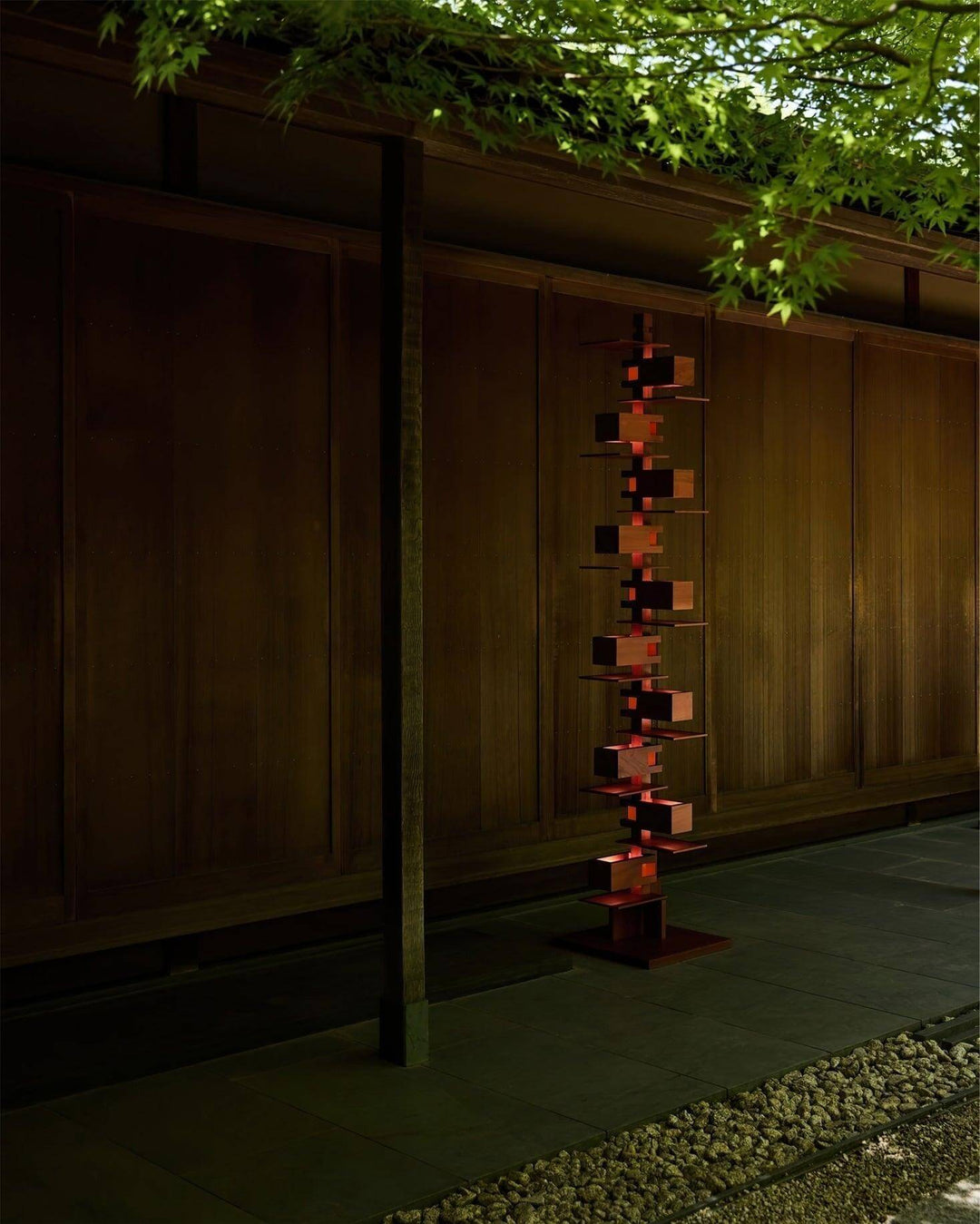 Elegant wooden floor lamp in an art deco style, illuminating a serene outdoor space with modern design.