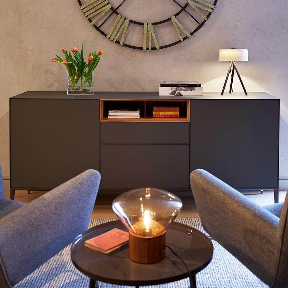 Modern living room setup featuring a round glass table lamp and stylish decor with a large wall clock.