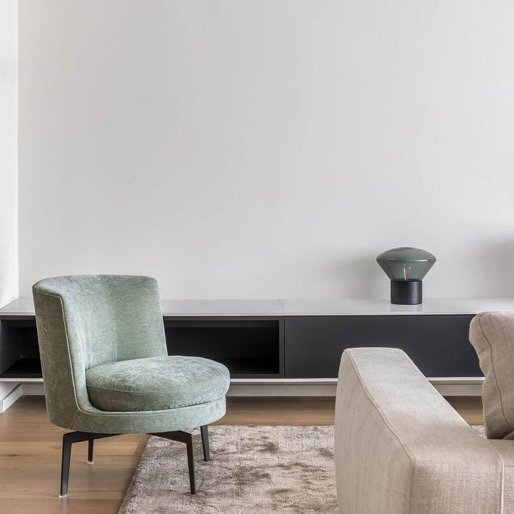 Art deco Muffins table lamp paired with a stylish green chair in a modern living room setting.