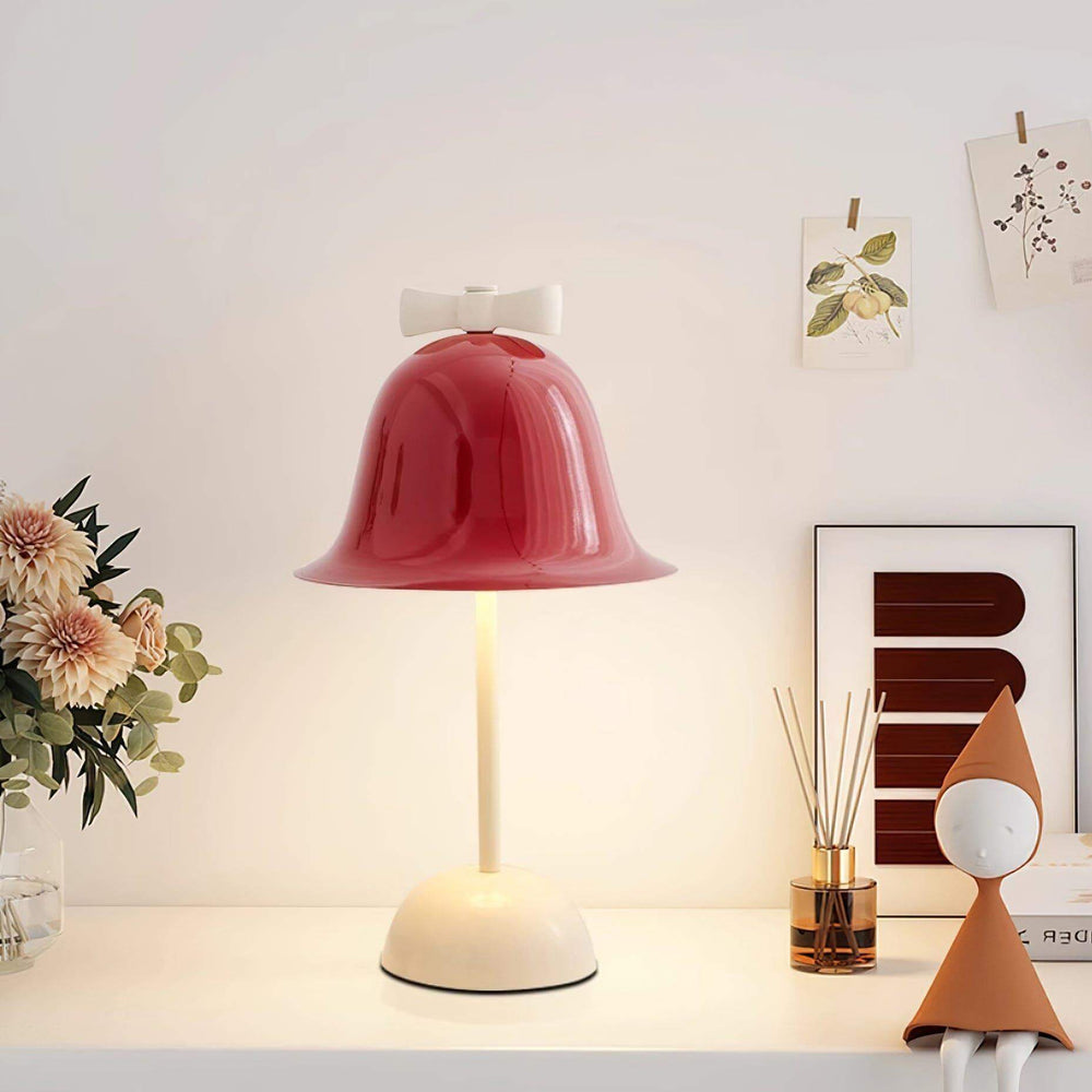 Colorful red bell-shaped lamp with white bow on a stylish table, perfect for bedside or dining room decor.